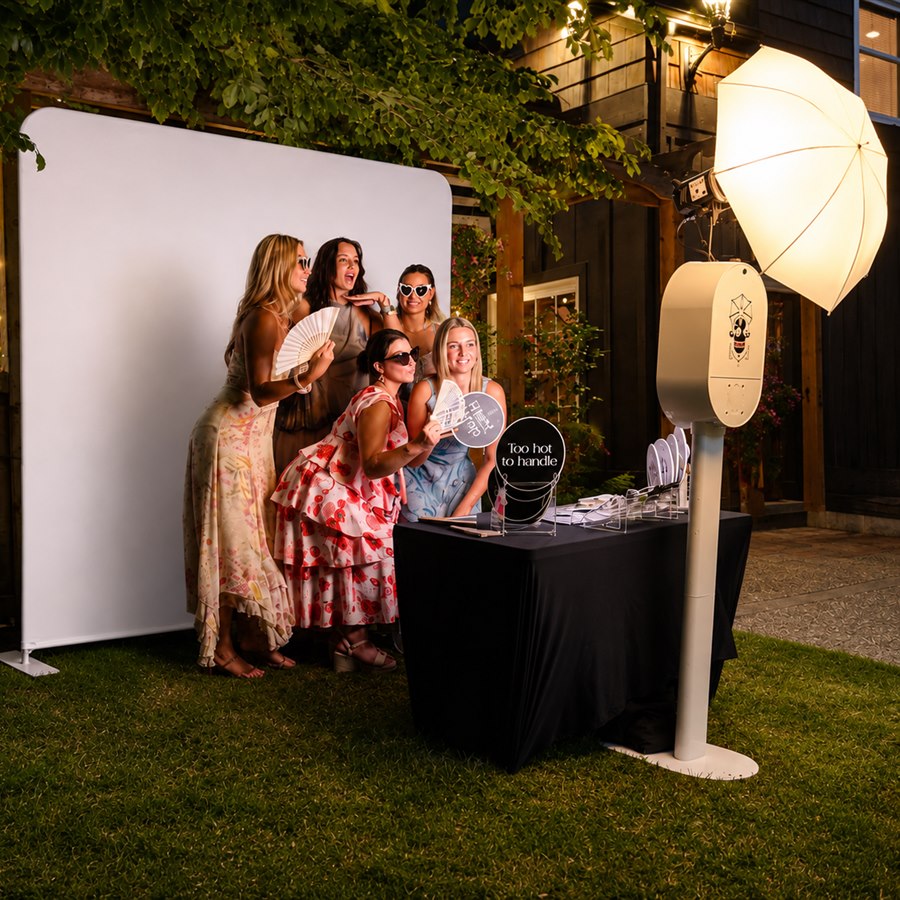 Guests posing at an outdoor evening photo booth with umbrella lighting