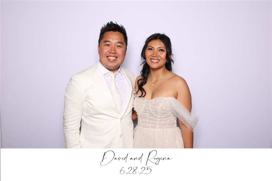 David and Regina posing together at their wedding reception photo booth