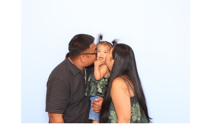 Family sharing a sweet kiss with their toddler at a birthday celebration photo booth