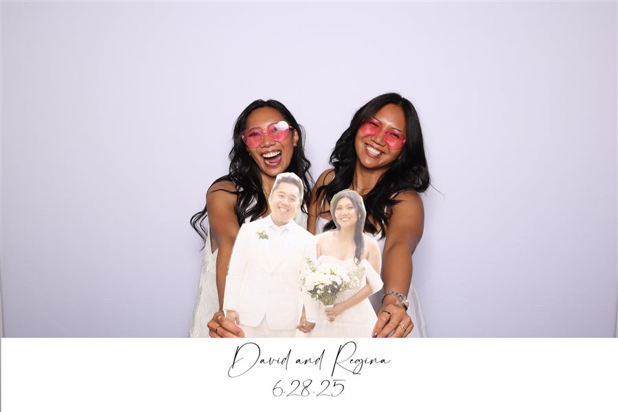 Guests posing with bride and groom cutouts at David and Regina's wedding photo booth