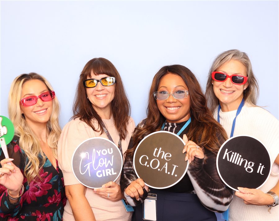 Attendees posing with fun signs at the Women at SPS Summit corporate event